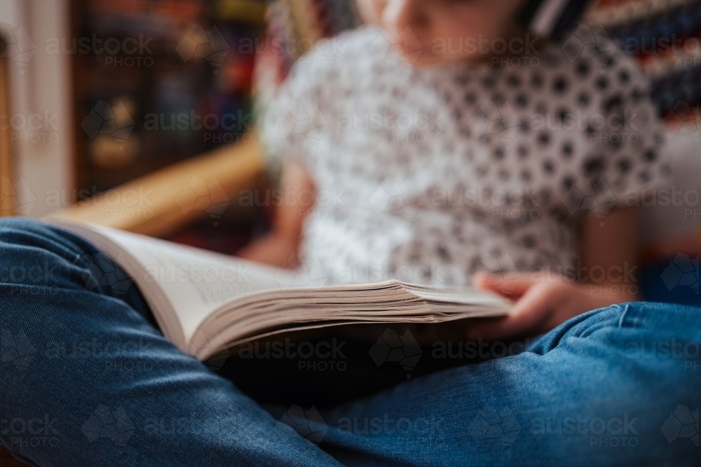 Young girl reading a book at home - Australian Stock Image