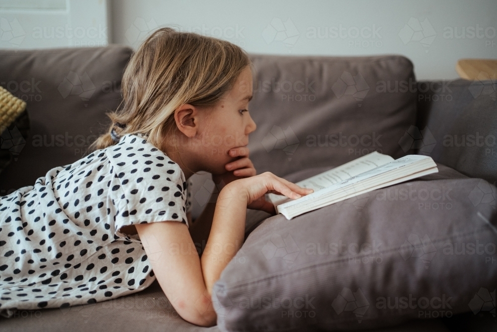 Young girl reading a book at home - Australian Stock Image