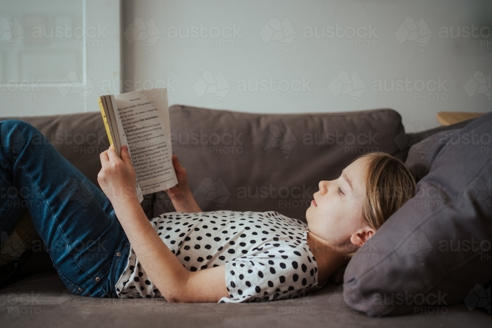 Young girl reading a book at home - Australian Stock Image