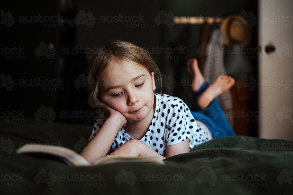 Young girl reading a book at home - Australian Stock Image