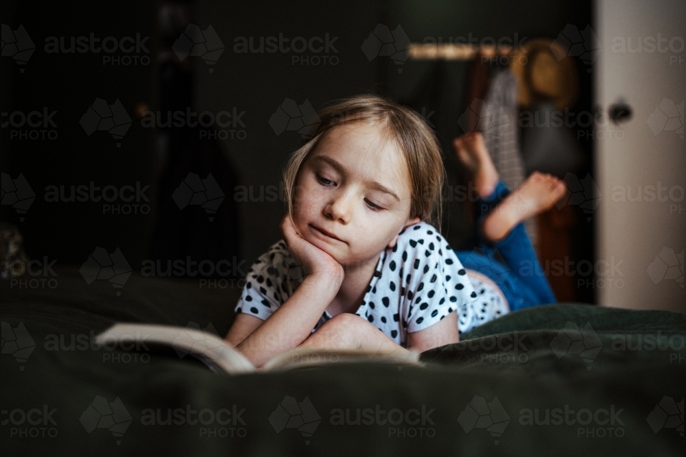 Young girl reading a book at home - Australian Stock Image