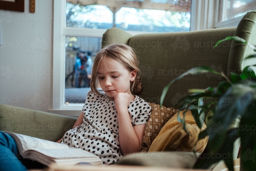 Young girl reading a book at home - Australian Stock Image