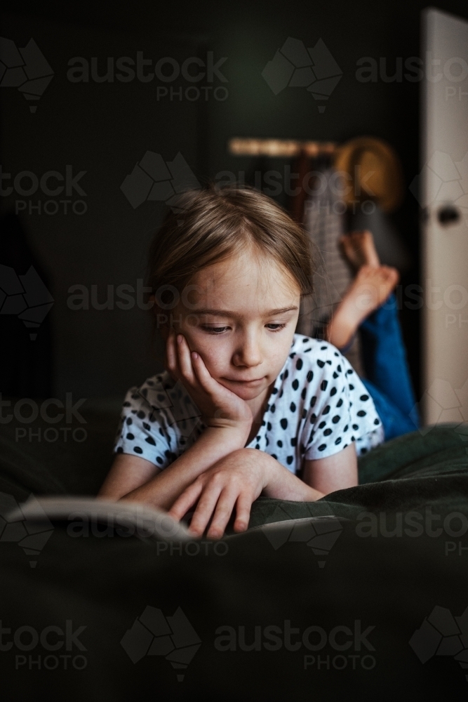 Young girl reading a book at home - Australian Stock Image