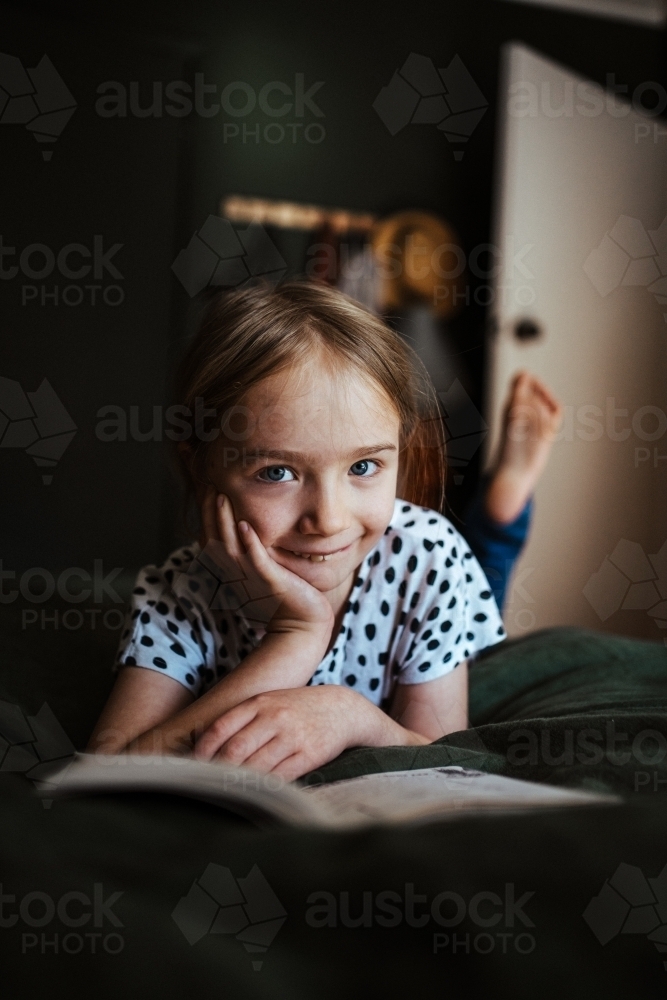 Young girl reading a book at home - Australian Stock Image