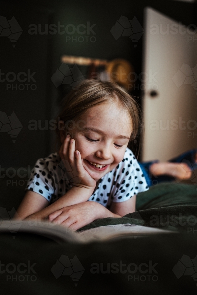 Young girl reading a book at home - Australian Stock Image