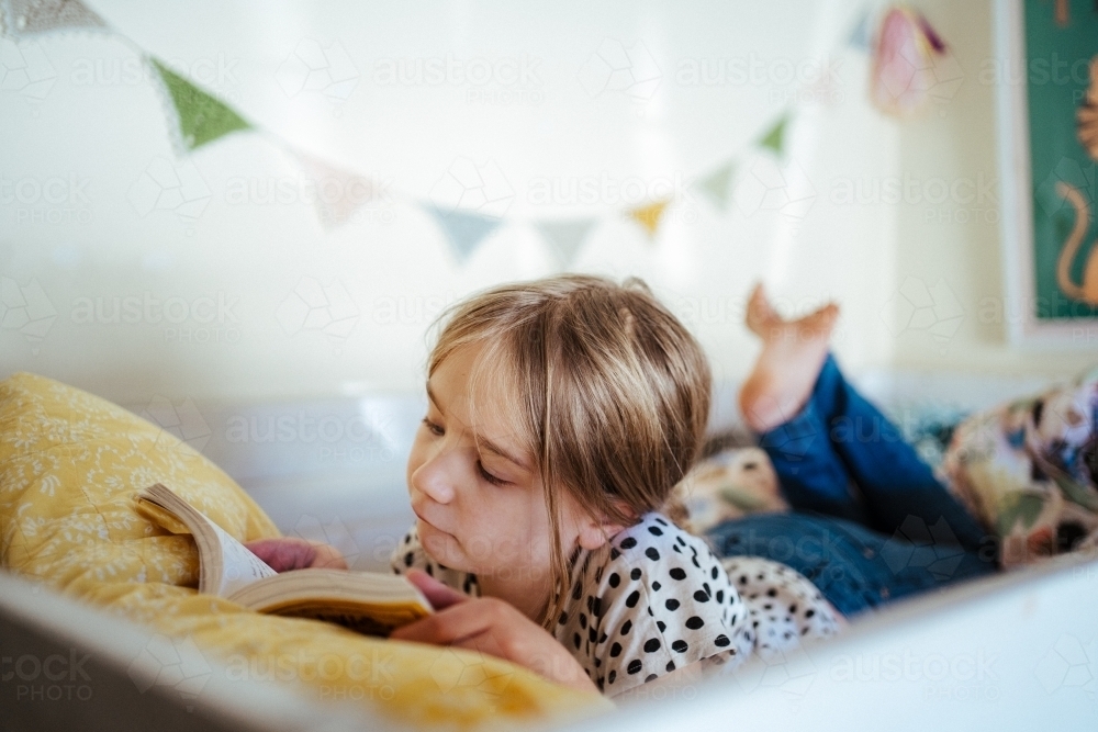 Young girl reading a book at home - Australian Stock Image