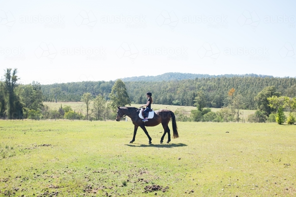 Young girl riding a horse in a paddock - Australian Stock Image