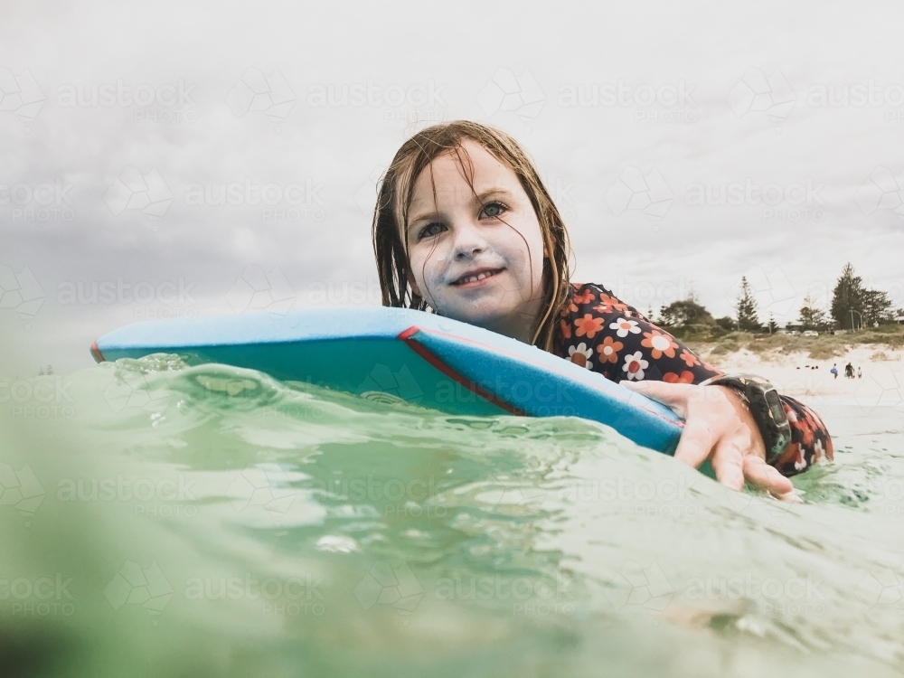 Young girl Riding boogie board in ocean - Australian Stock Image