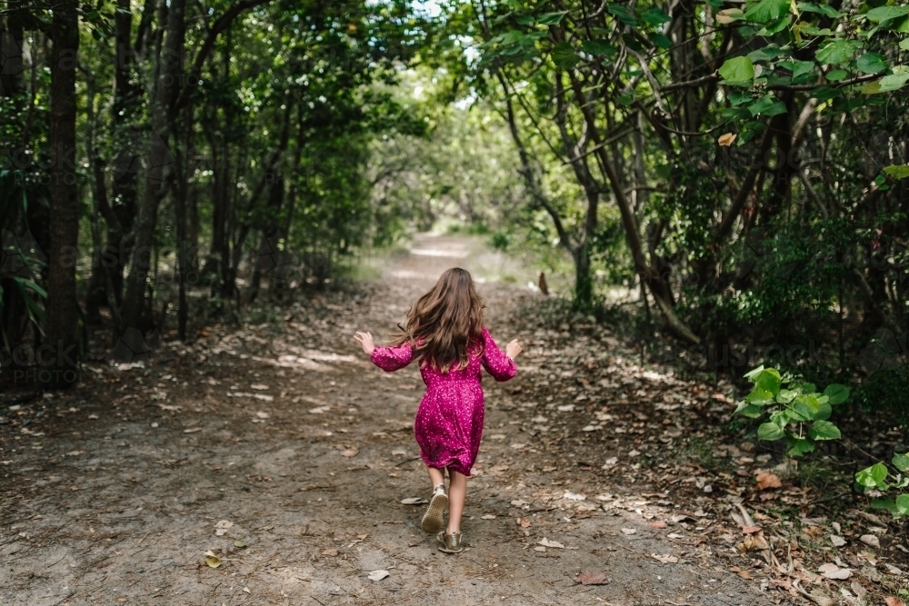 Image of Young girl running through along a bush path Austockphoto