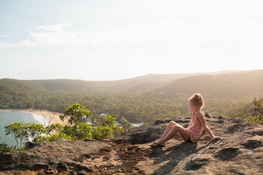 Young girl sitting on a rock looking at the view - Australian Stock Image
