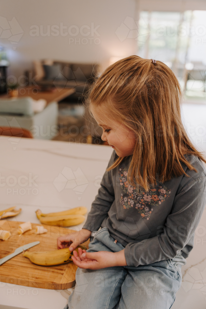 Young girl sitting on the kitchen countertop. - Australian Stock Image