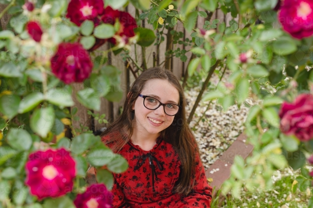 Young girl sitting under a rose bush - Australian Stock Image