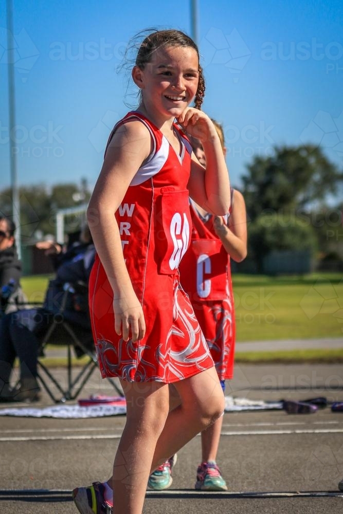 Young girl smiling after winning game for netball team - Australian Stock Image
