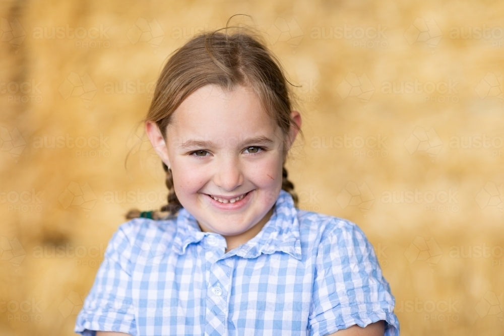 young girl smiling bashfully looking at camera with blurry background - Australian Stock Image