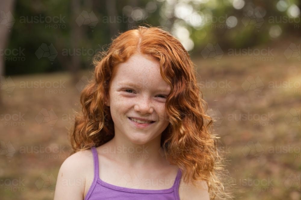 Young girl smiling in an open field - Australian Stock Image