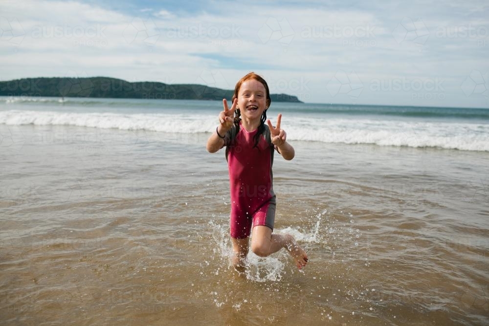 Young girl smiling in the water at the beach - Australian Stock Image