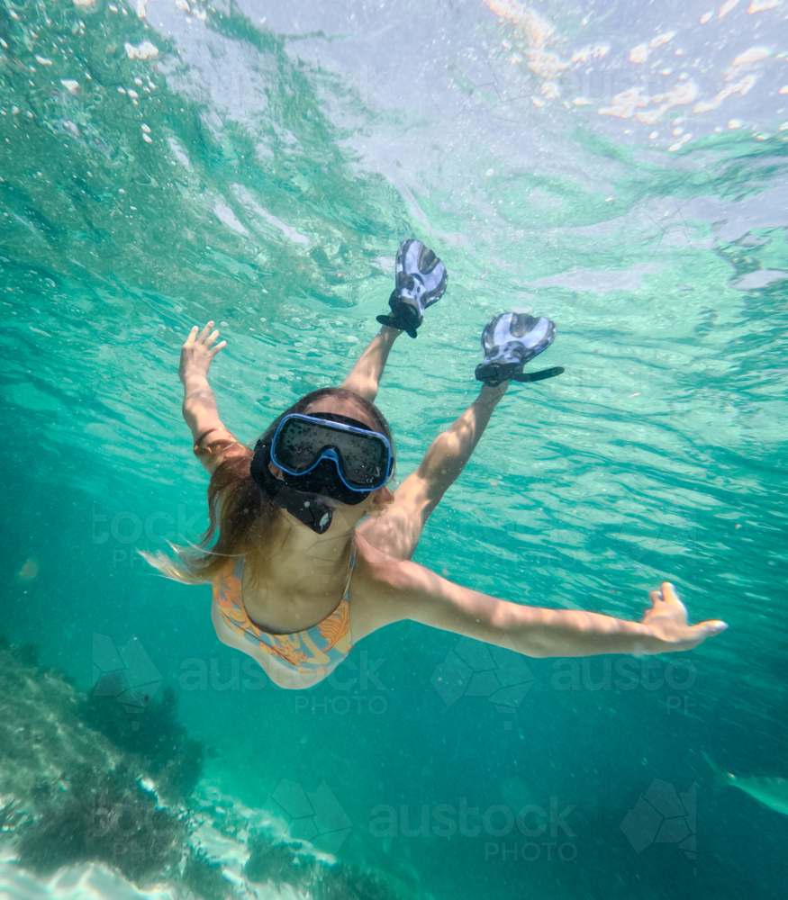 Young girl snorkeling diving down in clear ocean - Australian Stock Image