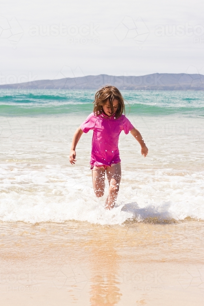 Young girl splashing through waves - Australian Stock Image