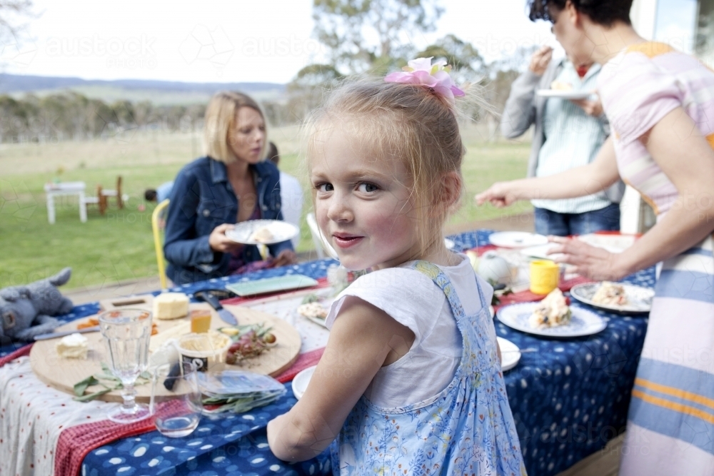 Young girl standing at a table outside on Christmas day - Australian Stock Image