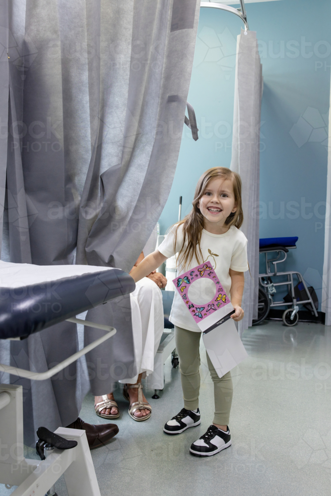 Young girl standing behind curtains holding a notebook - Australian Stock Image