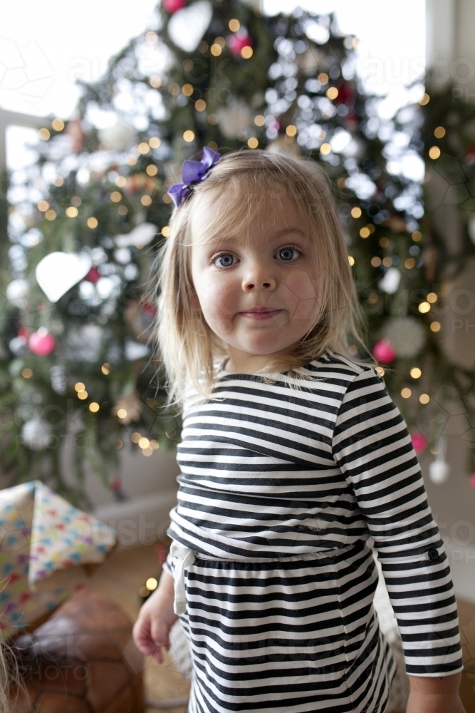 Young girl standing in front of Christmas tree - Australian Stock Image