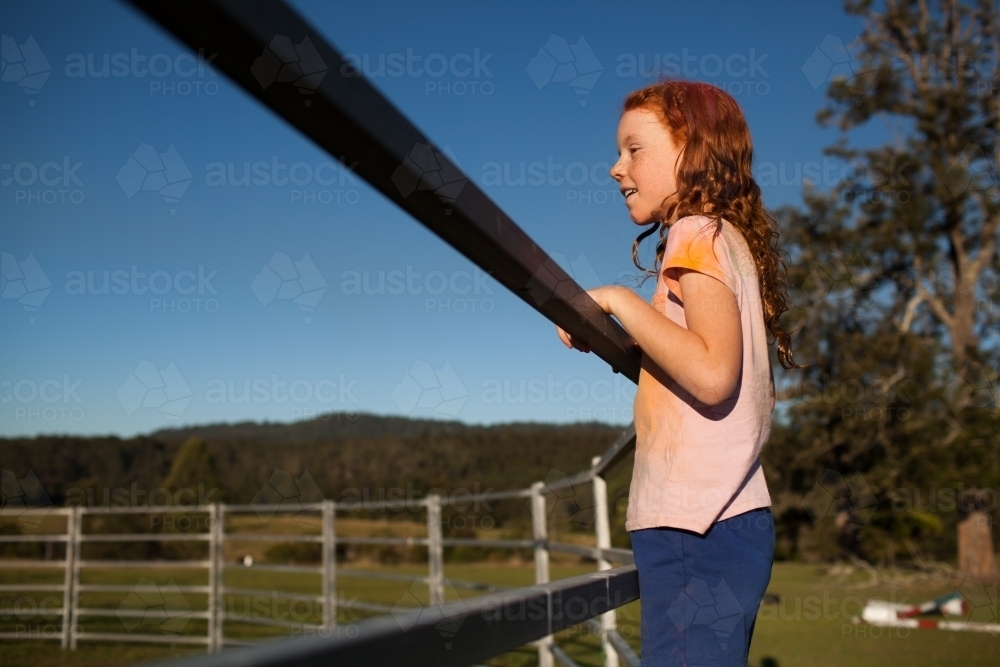 Young girl standing on a metal fence - Australian Stock Image