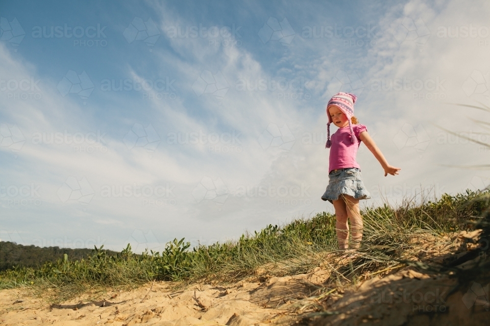 Young girl standing on a sand dune in a pink beanie - Australian Stock Image