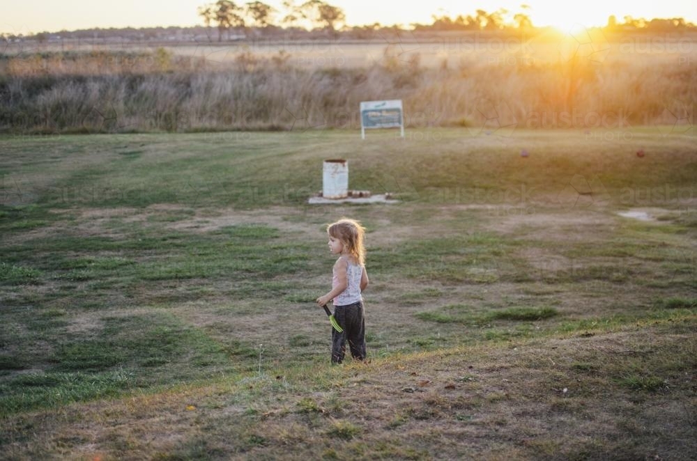 Young girl standing on rural golf course at sunset - Australian Stock Image
