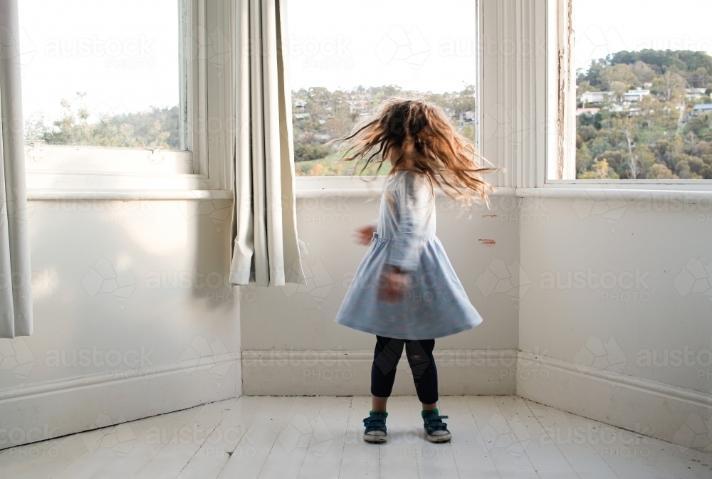 Young girl standing spinning in an empty room - Australian Stock Image