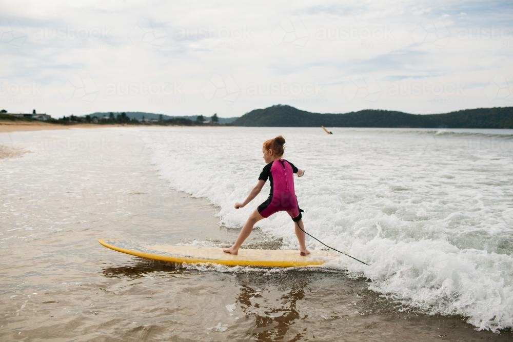 Young girl surfing at the beach - Australian Stock Image