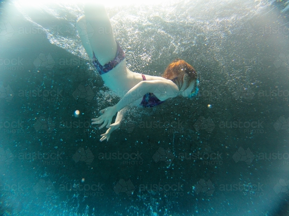 Young girl swimming underwater at a pool - Australian Stock Image