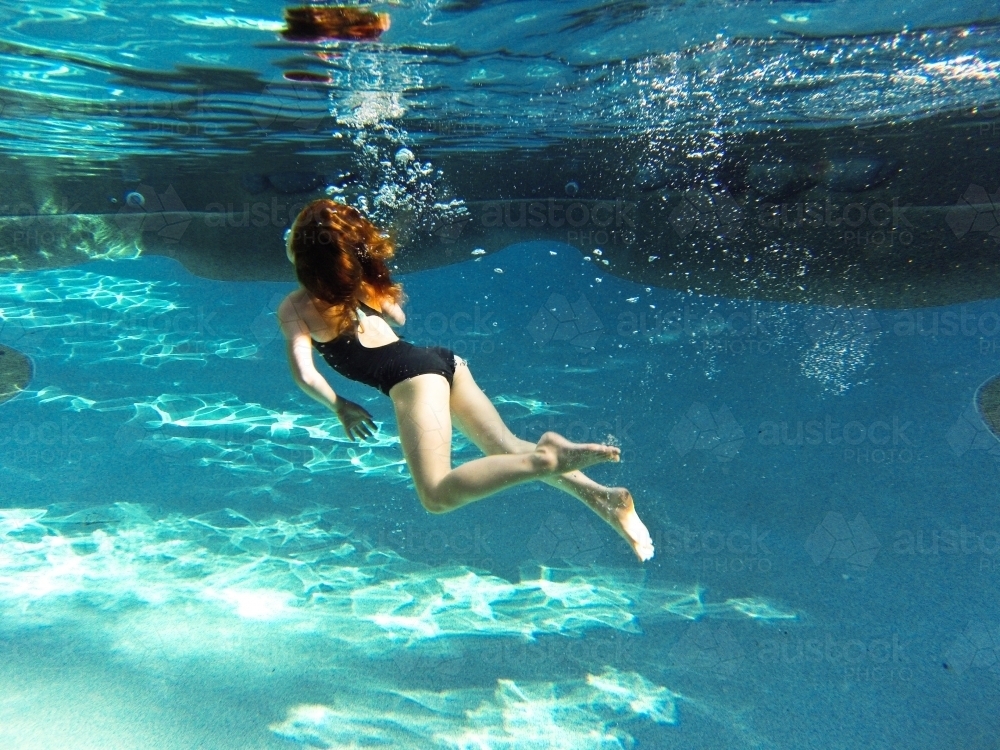 Young girl swimming underwater at a pool - Australian Stock Image