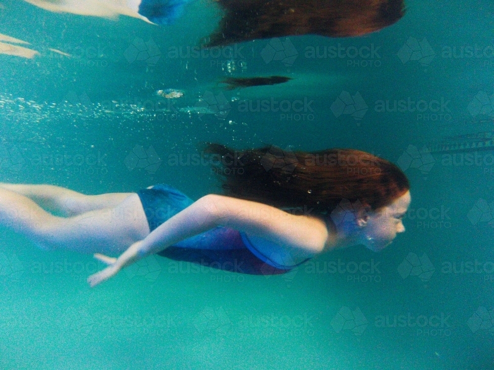 Young girl swimming underwater in the pool - Australian Stock Image