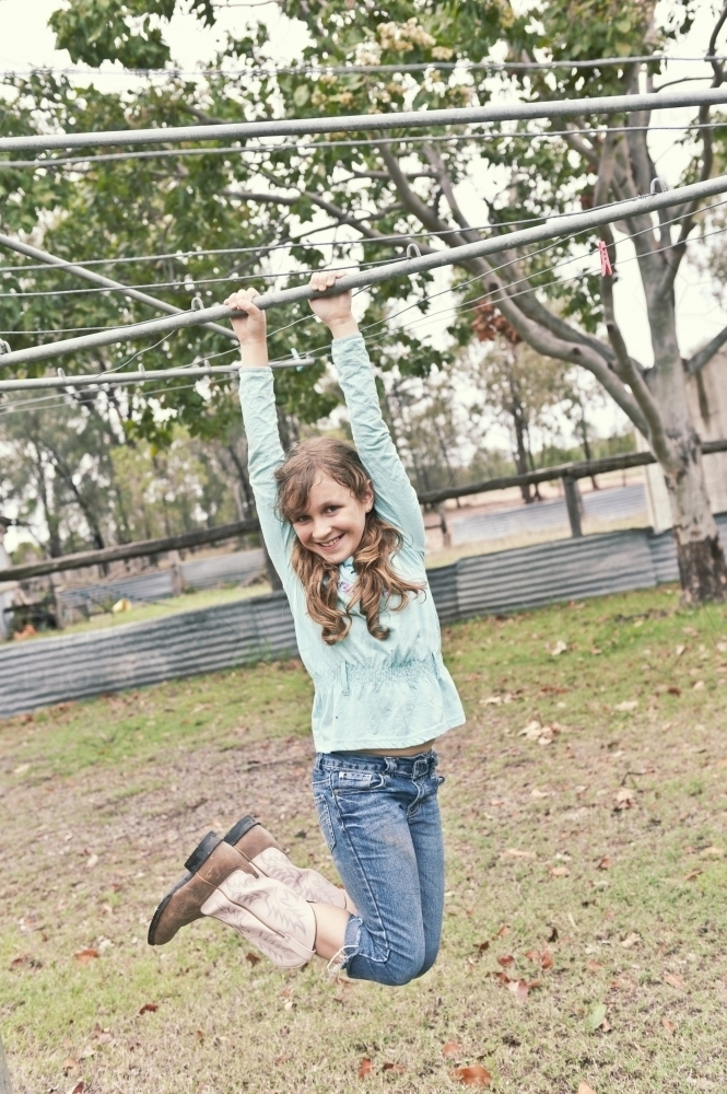 Young girl swinging on hills hoist - Australian Stock Image
