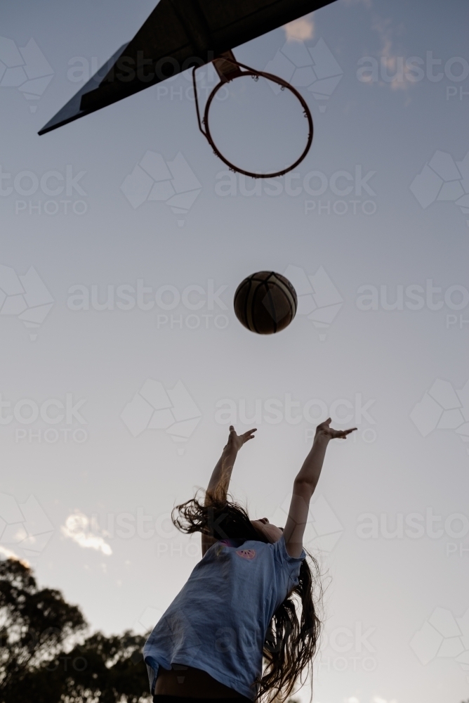 Young girl throwing a basketball into a basketball ring / hoop - Australian Stock Image