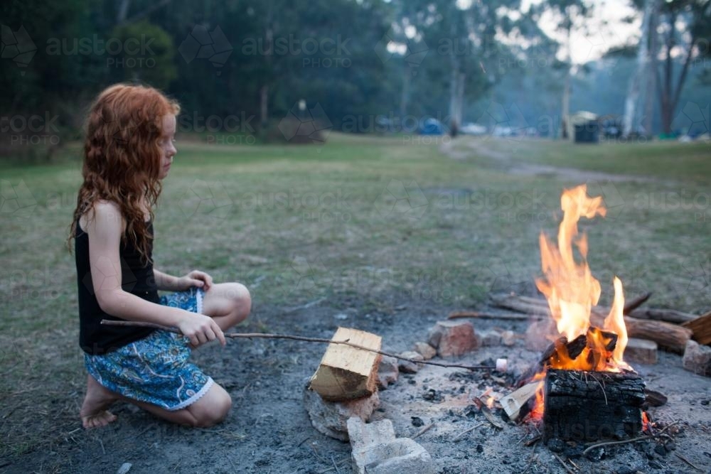 Young girl toasting a marshmallow on a campfire - Australian Stock Image