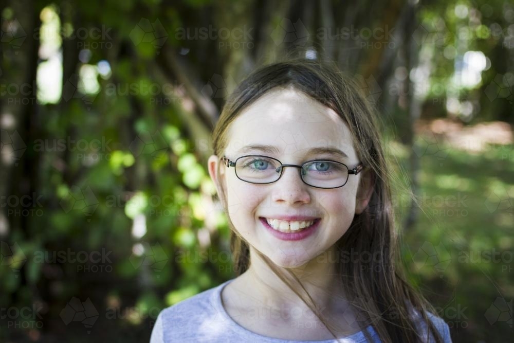 Young girl under trees smiling - Australian Stock Image
