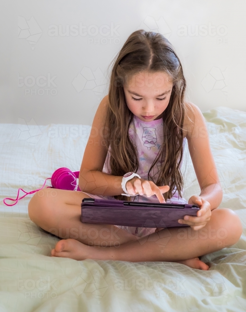 Young girl using technology doing her homework on a tablet - Australian Stock Image