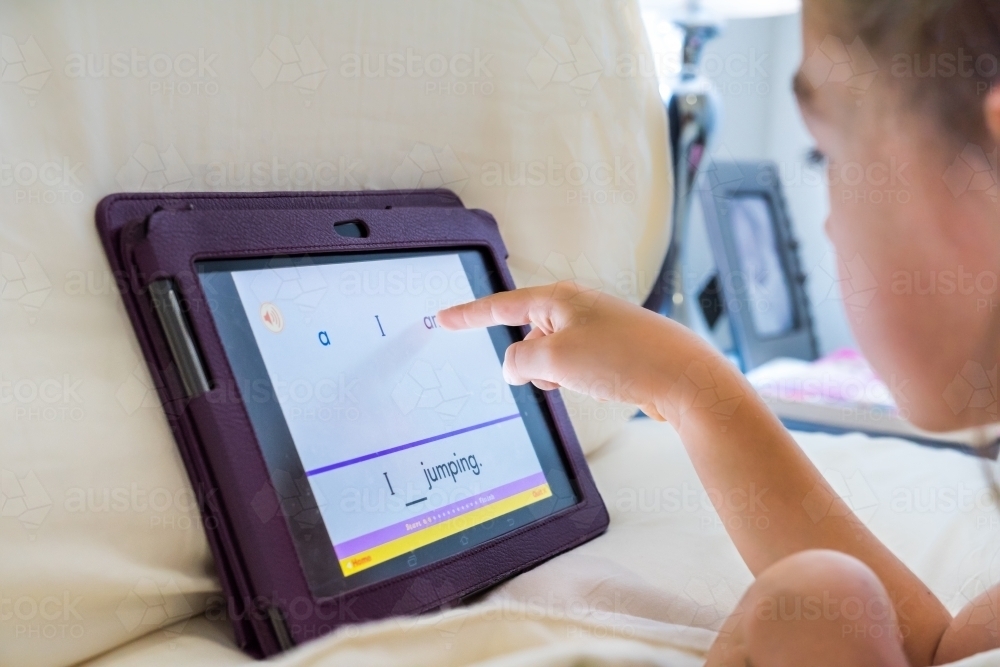 Young girl using technology to do her homework by using a smart device - Australian Stock Image