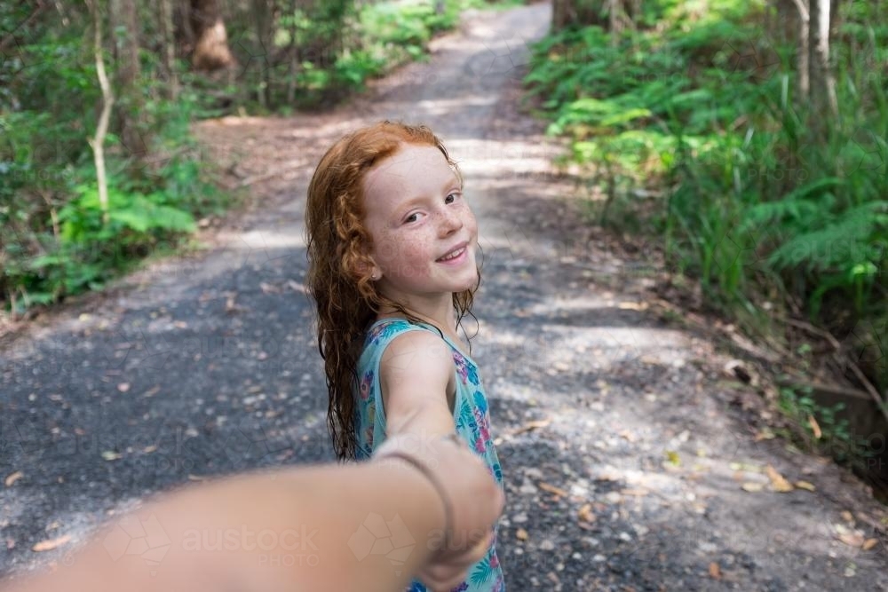 Young girl walking along a bush track holding hands - Australian Stock Image