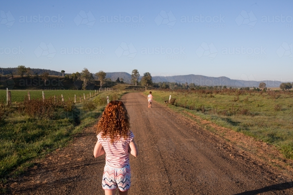 Young girl walking along a dirt rural road - Australian Stock Image