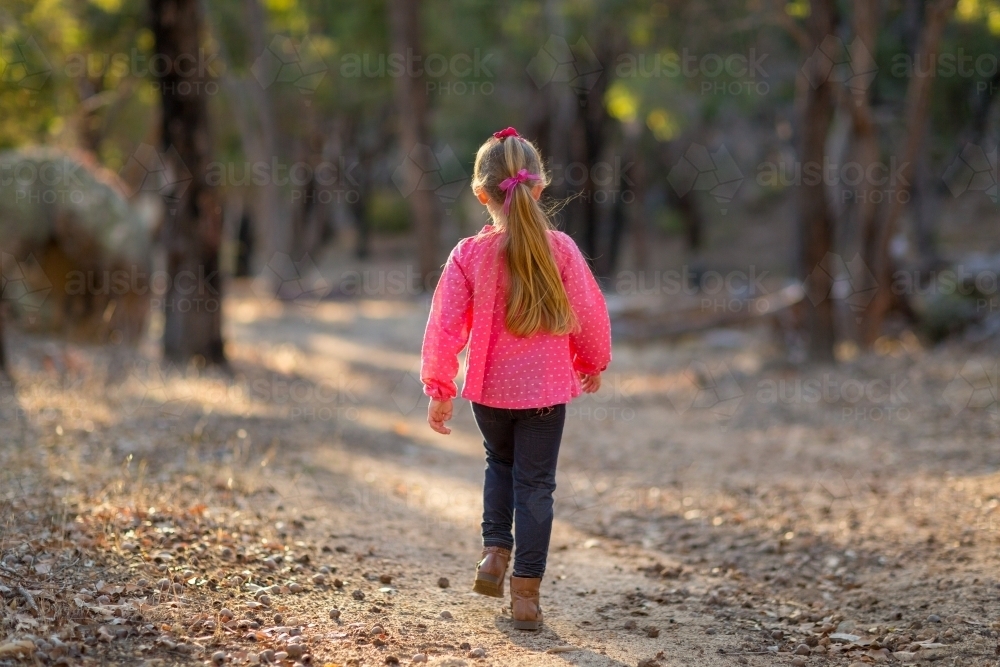 Young girl walking away down a track in the bush - Australian Stock Image