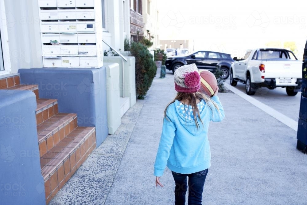 Young girl walking down street with basketball - Australian Stock Image
