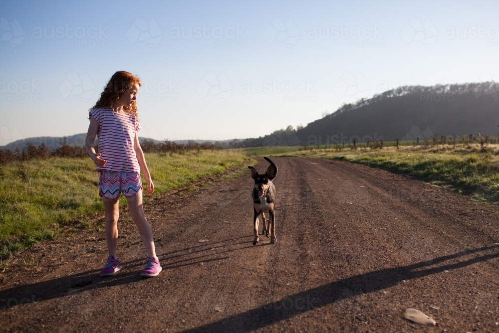 Young girl walking her dog on a dirt road - Australian Stock Image