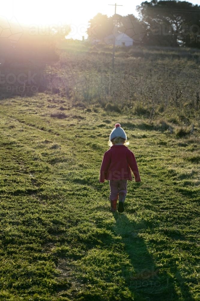 Young girl walking in a paddock in winter with sunshine - Australian Stock Image