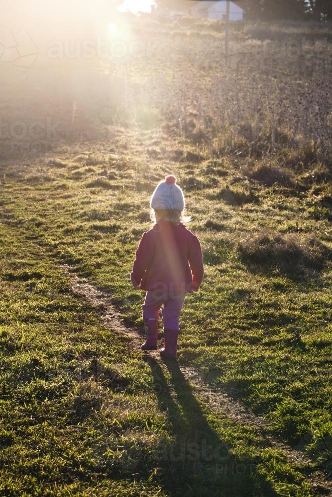 Young girl walking in a paddock in winter with sunshine - Australian Stock Image