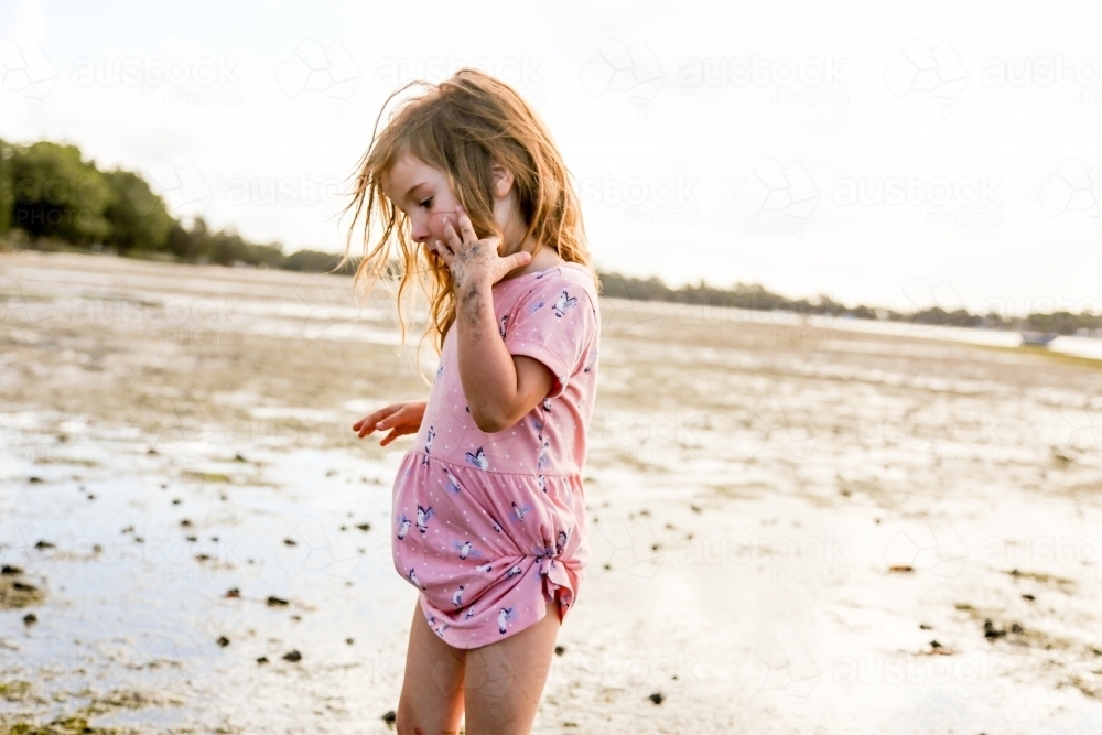 Young girl wandering along and exploring the edge of the ocean - Australian Stock Image