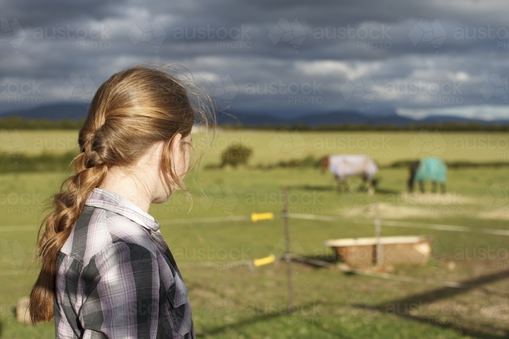 Young girl watching horses at horse riding farm - Australian Stock Image
