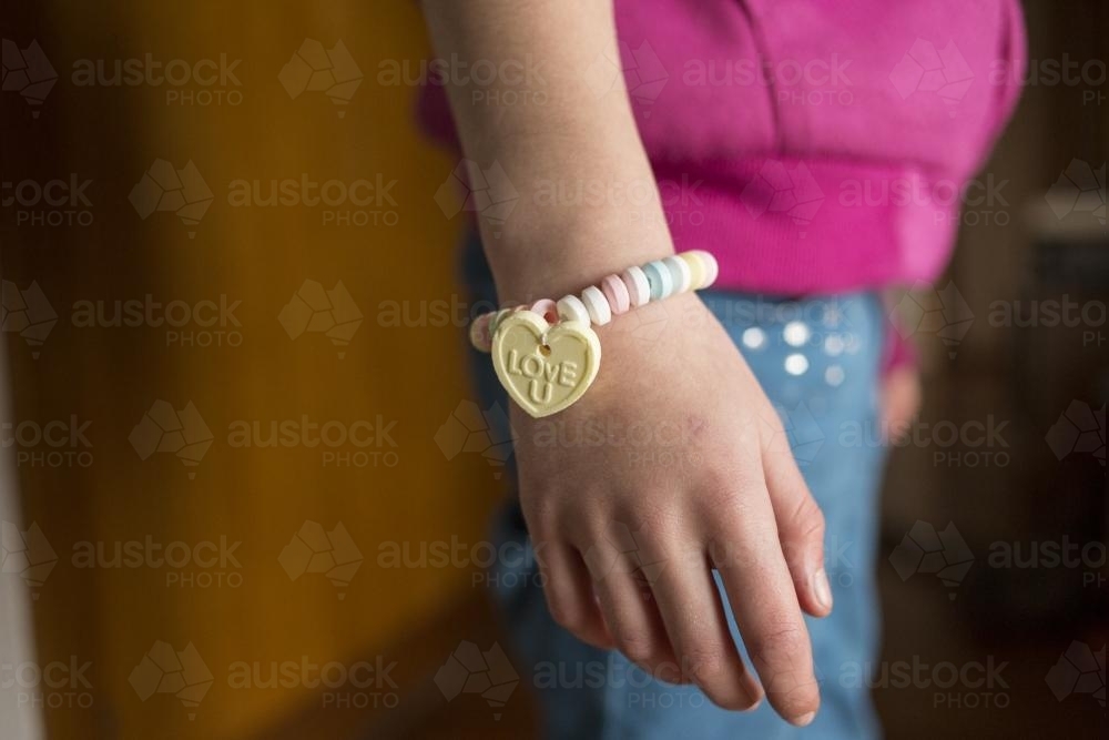 Young girl wearing candy bracelet hand only - Australian Stock Image