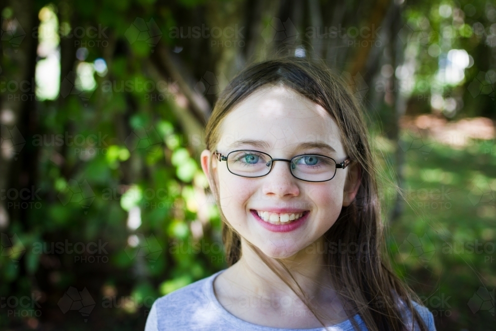 Young girl wearing glasses in dappled light - Australian Stock Image